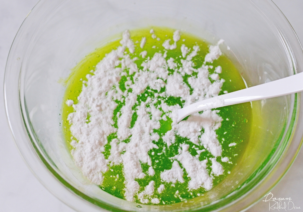 baking soda sprinkled on top of green glue for slime making