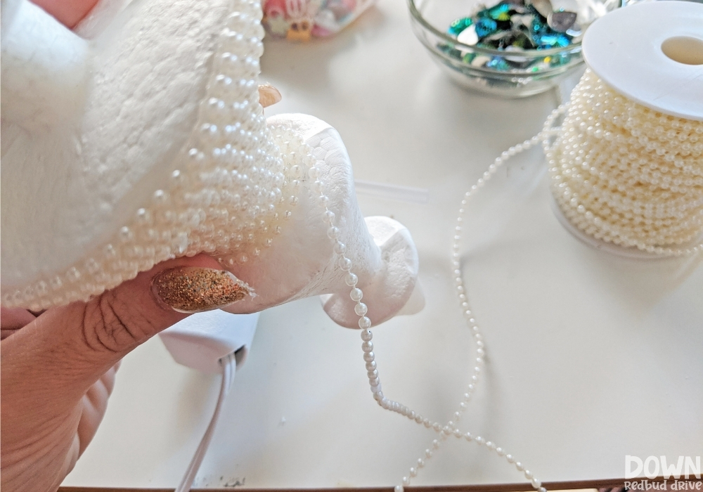 A foam Christmas tree form wrapped half way with a pearl strand.