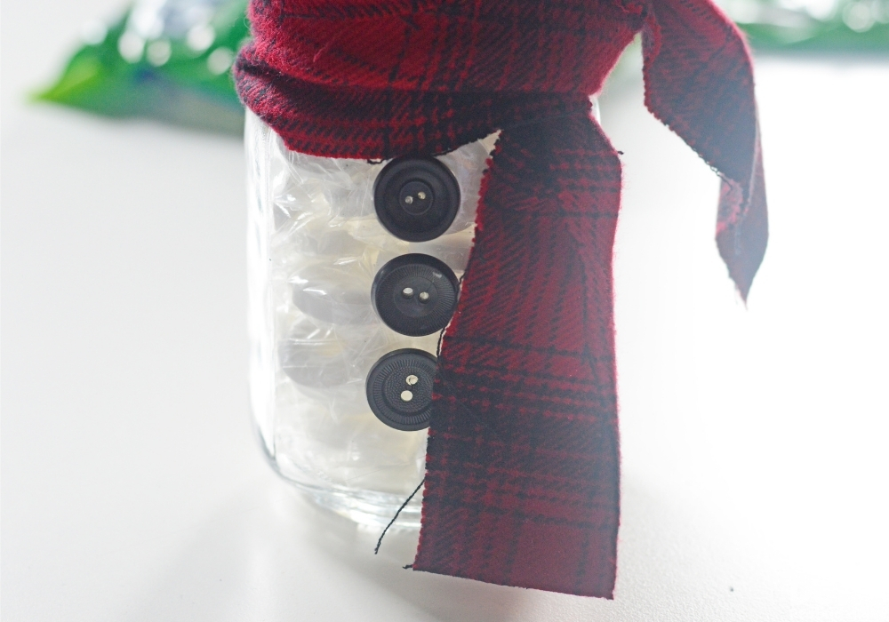 3 black buttons added to the front of the mason jar to make it look like a snowman.