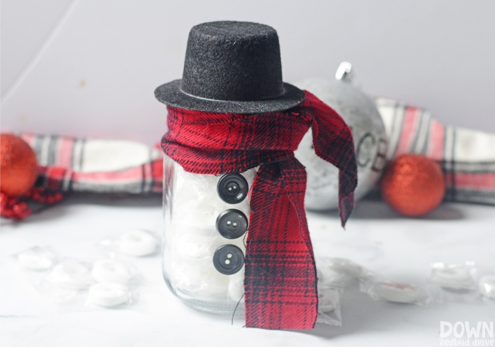 The finished DIY Lifesaver Snowman Gift with Christmas ornaments and plaid in the background.