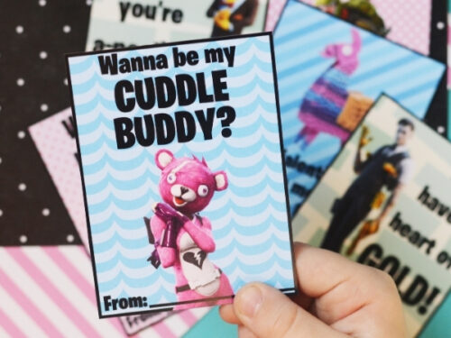 A child holding a Fortnite valentine that says "Wanna be my cuddle buddy?" on it.