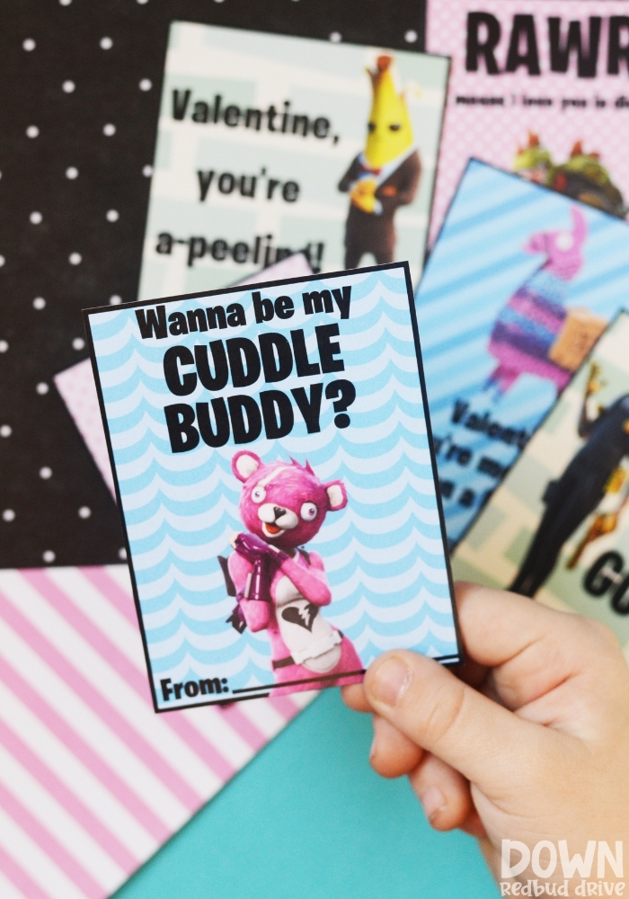 Close up of a child holding a Fortnite valentine that says "Wanna be my cuddle buddy?" on it.