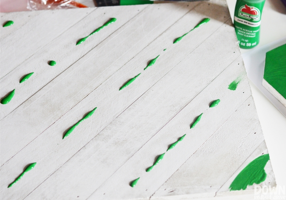 Green paint dripped across a square wooden sign.