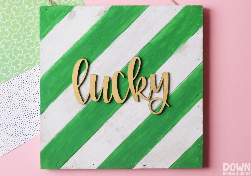 Overhead view of the finished DIY Wooden Lucky Sign on a pink background.