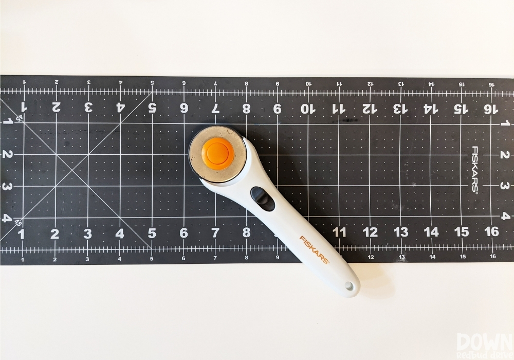 A fabric rotary cutter sitting on a rotary cutting mat.