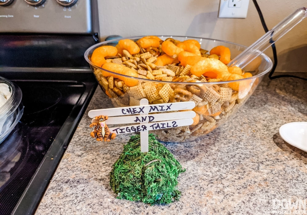 A bowl of snacks with a sign that says "Chex Mix and Tigger Tails".