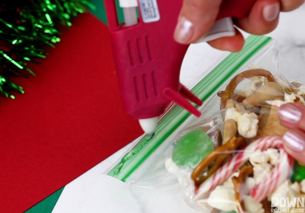 Hot glue being put on a resealable bag of snacks to attach a printable tag.