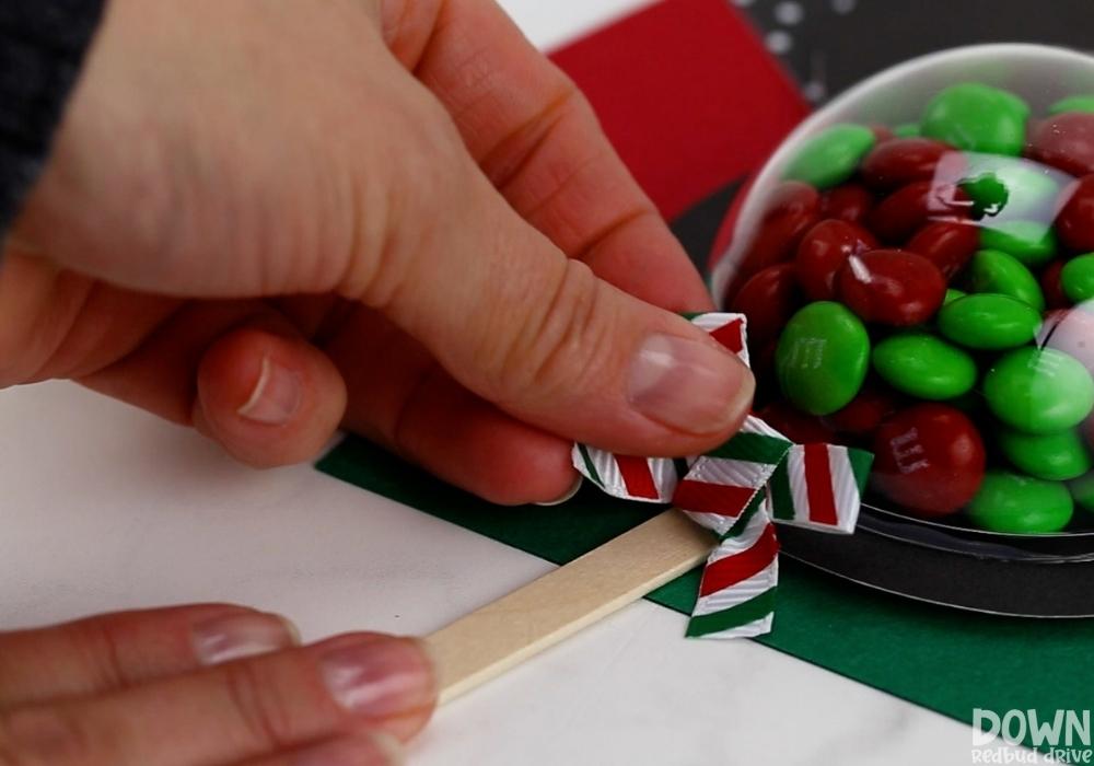 A Christmas bow being glued to an M&M pop.