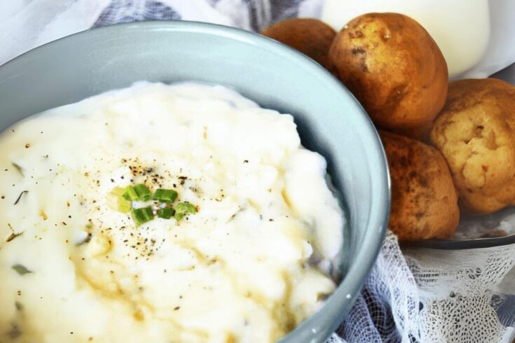 easy old fashioned potato soup recipe in a blue bowl next to a pile of potatoes