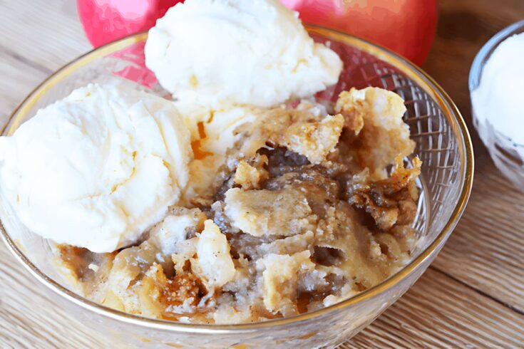 homemade apple crisp in a clear bowl topped with vanilla ice cream