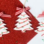Several finished Little Debbie Christmas tree ornaments made of wood against a festive Christmas red glitter paper