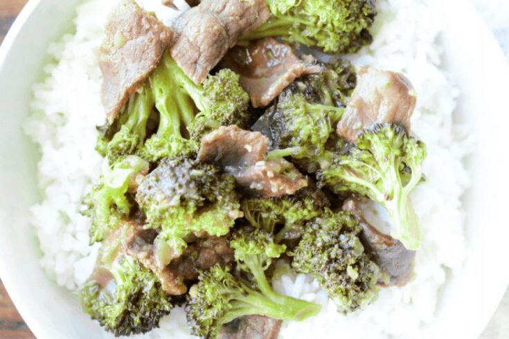 finished slow cooker beef and broccoli on a bed of rice in a white bowl.