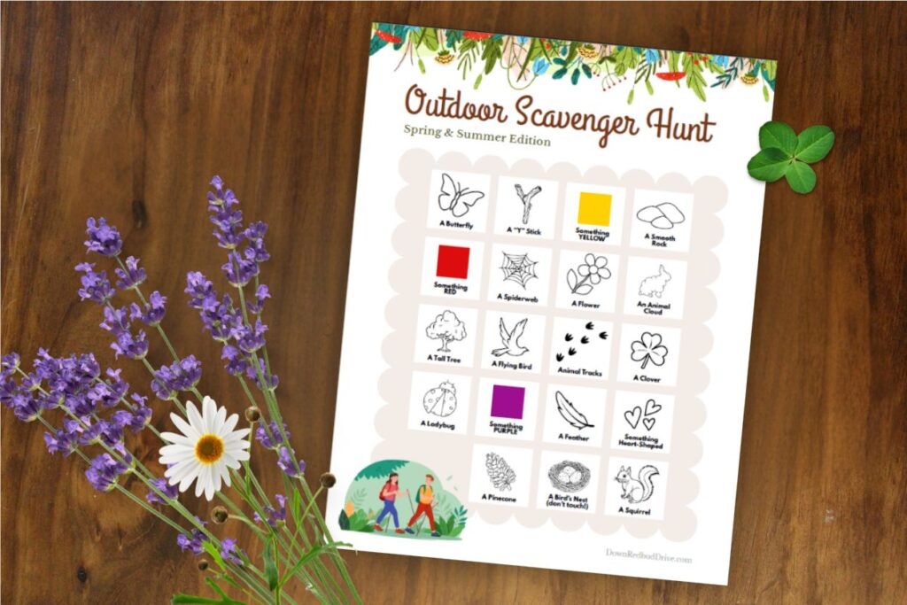 The free outdoor scavenger hunt printable on a wooden table with wild flowers and clover around the page.