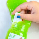 A close up of a jar of finished elf snot with a gift card being pulled out of the snot. A text overlay reads funny gift card prank elf snot recipe and printable tags